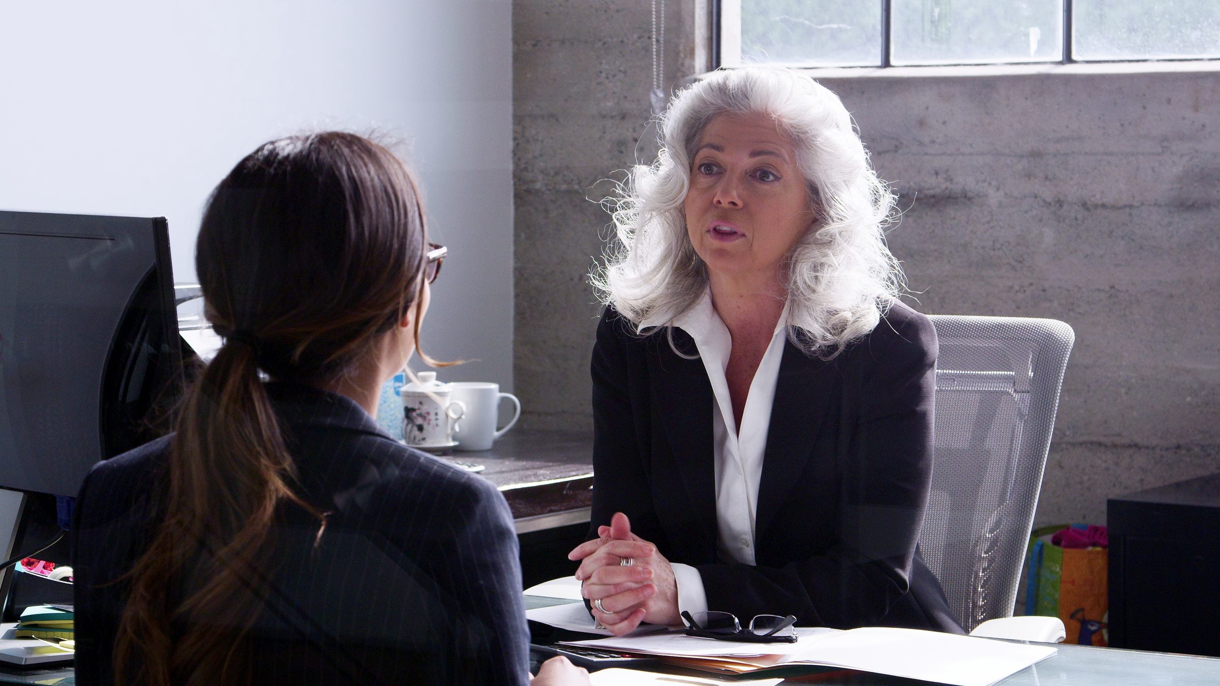 Two women in a one-on-one office meeting, the senior advisor gesturing as she talks