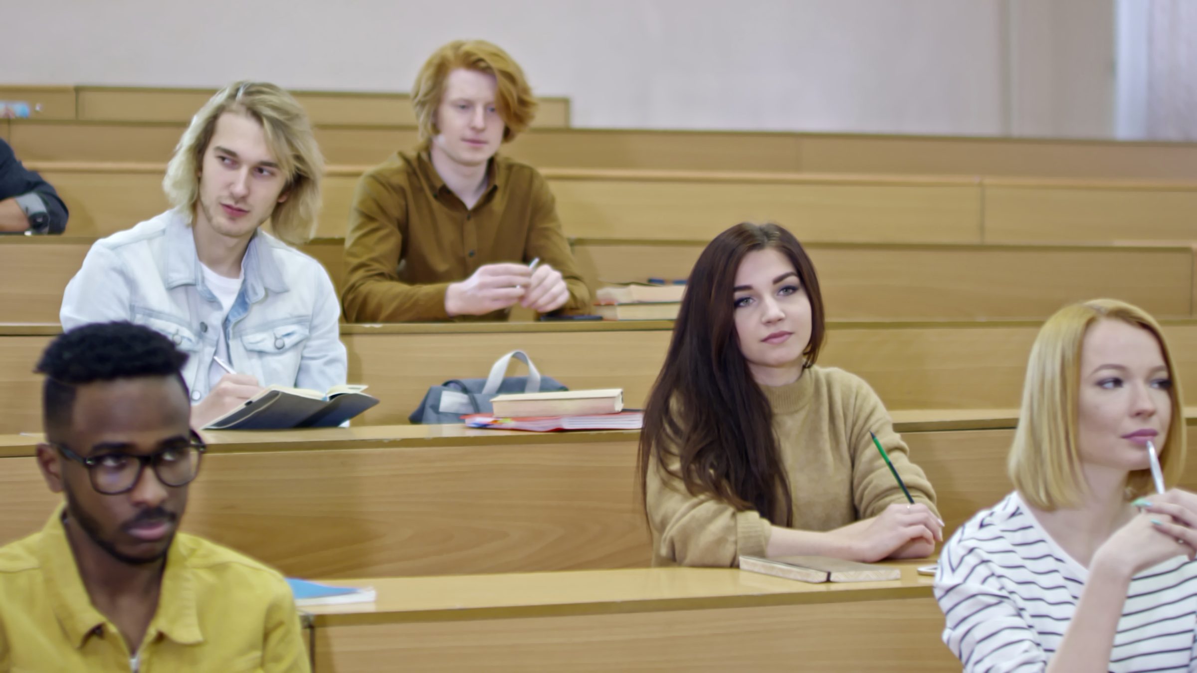 Students sit in a wood-paneled lecture hall facing the front